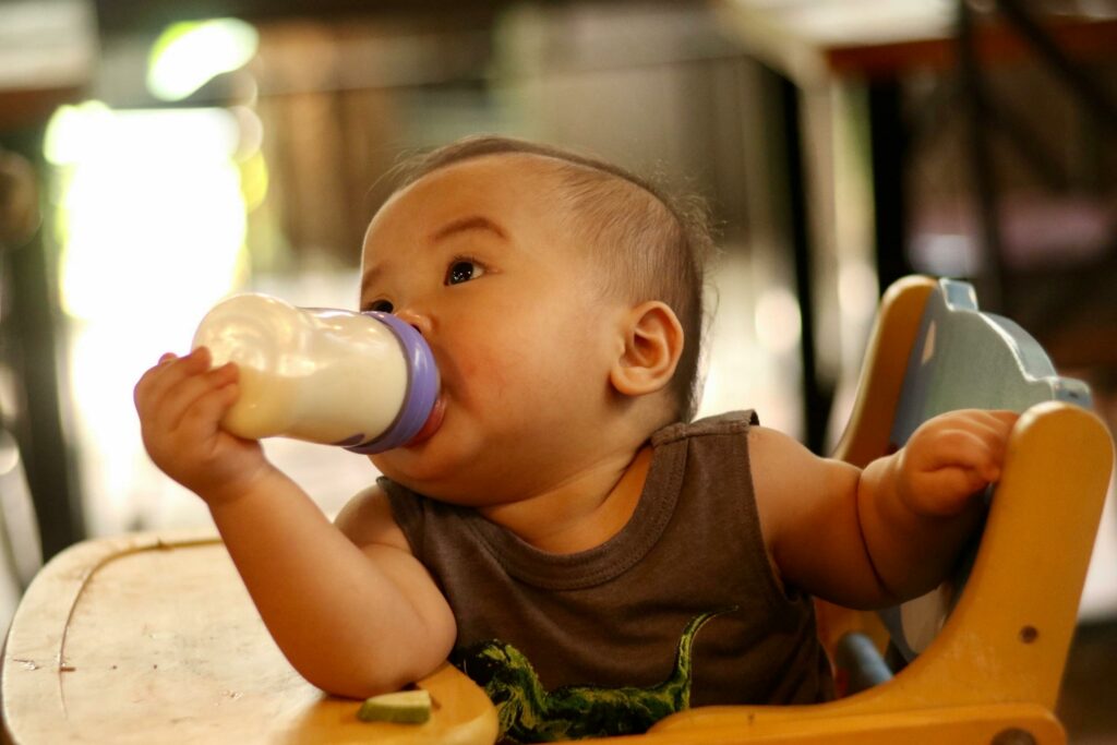 share the drop - baby in high chair drinking from a baby bottle