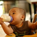 share the drop - baby in high chair drinking from a baby bottle